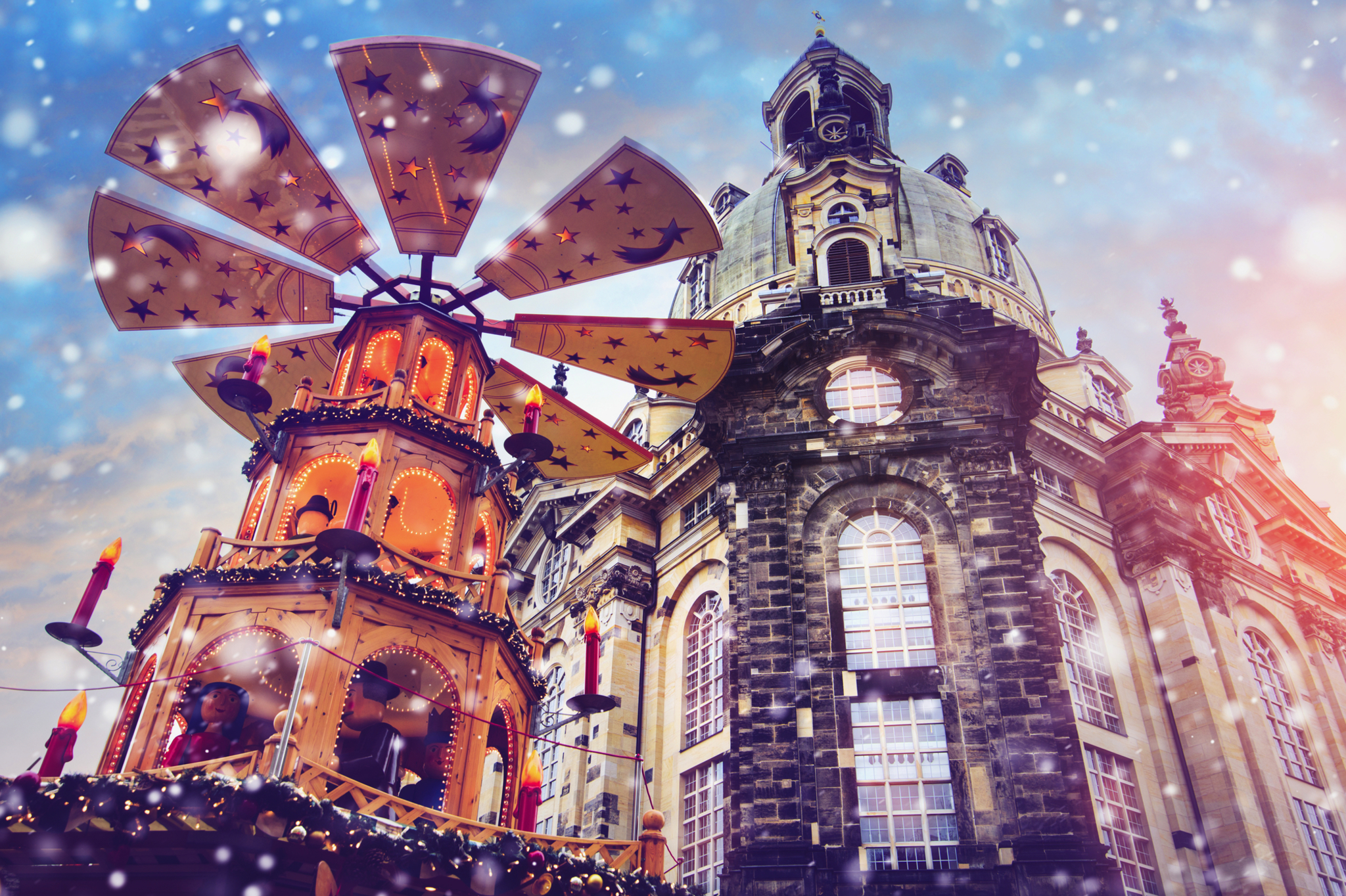 Weihnachtsmarkt in Dresden, Deutschland Weihnachtspyramide vor historischer Kirche mit Schneefall im Hintergrund.