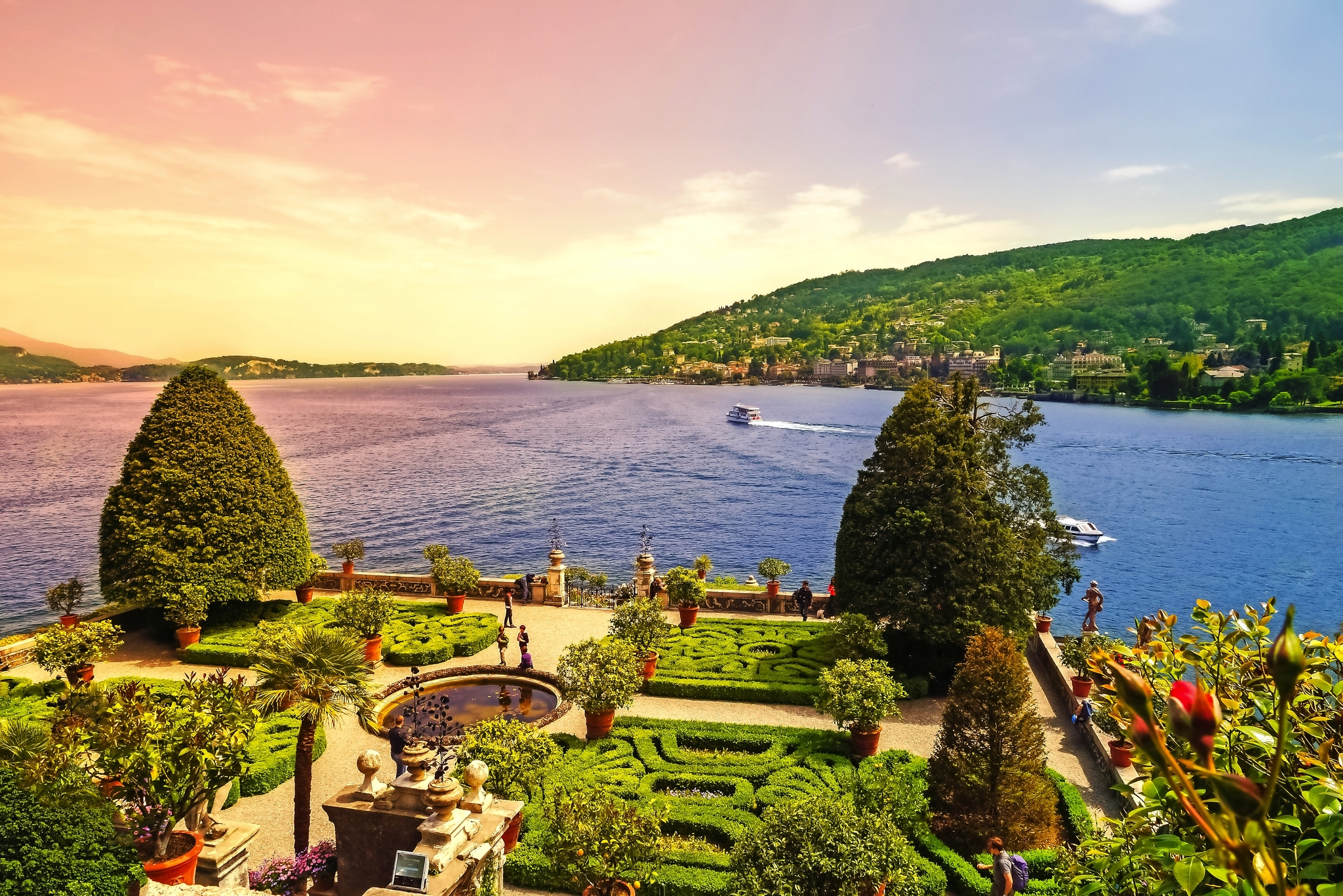 Gepflegter Garten mit Seeblick und grünen Hügeln im Hintergrund.
