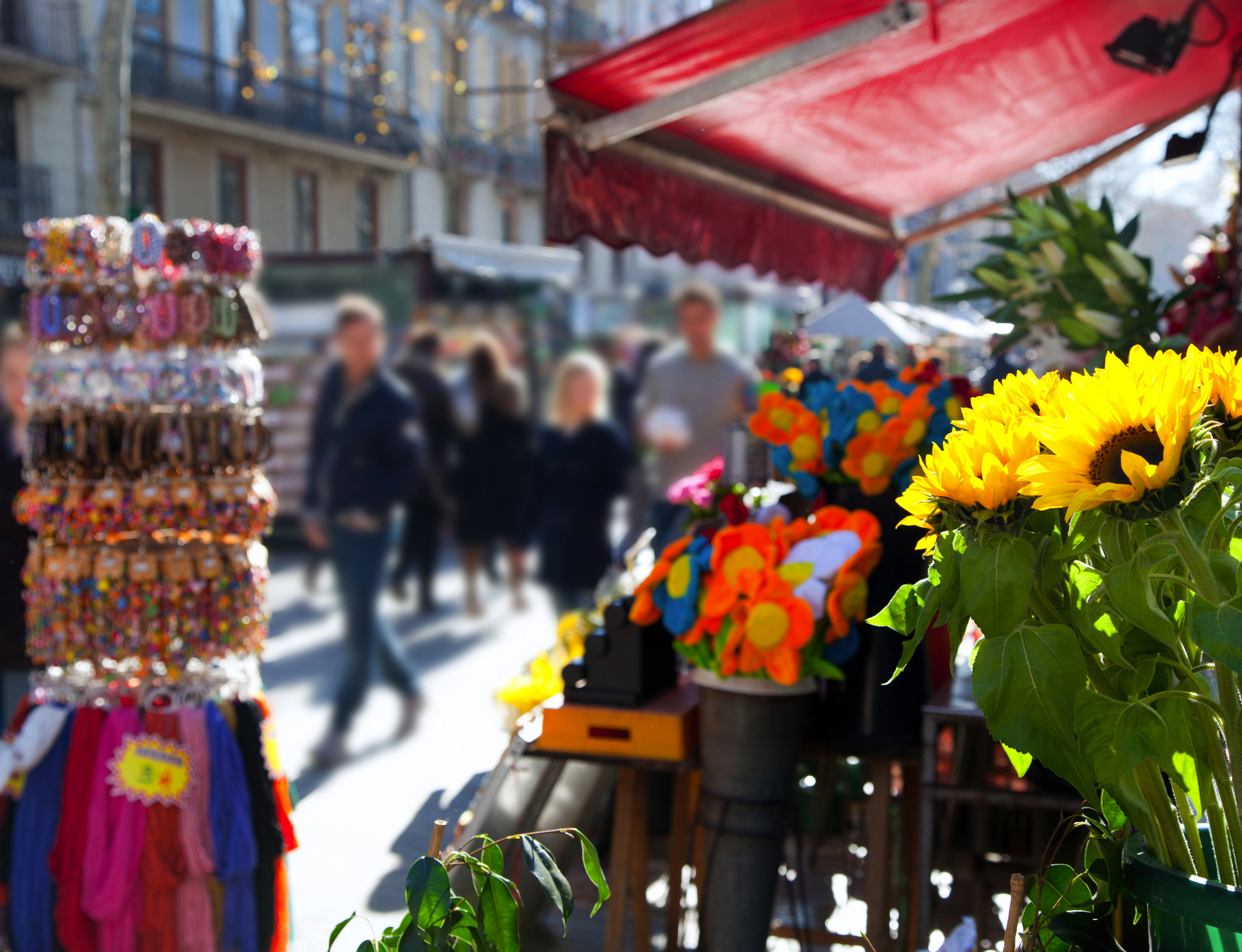 La Rambla in Barcelona, Spanien Marktstand mit Blumen und Schmuck, unscharfe Passanten im Hintergrund.