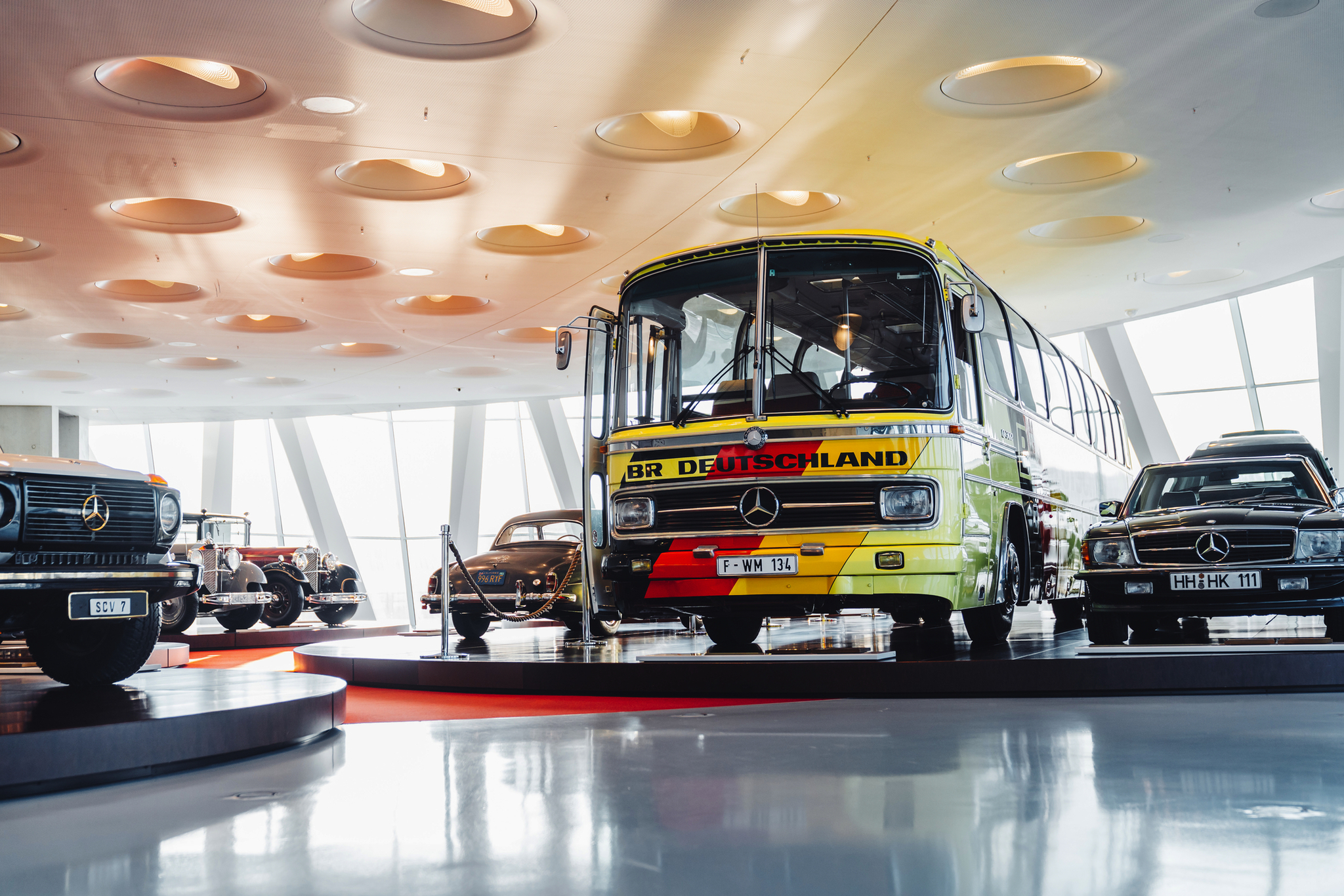 Mercedes-Benz Museum Oldtimer-Bus in Museum mit weiteren klassischen Fahrzeugen im Hintergrund.