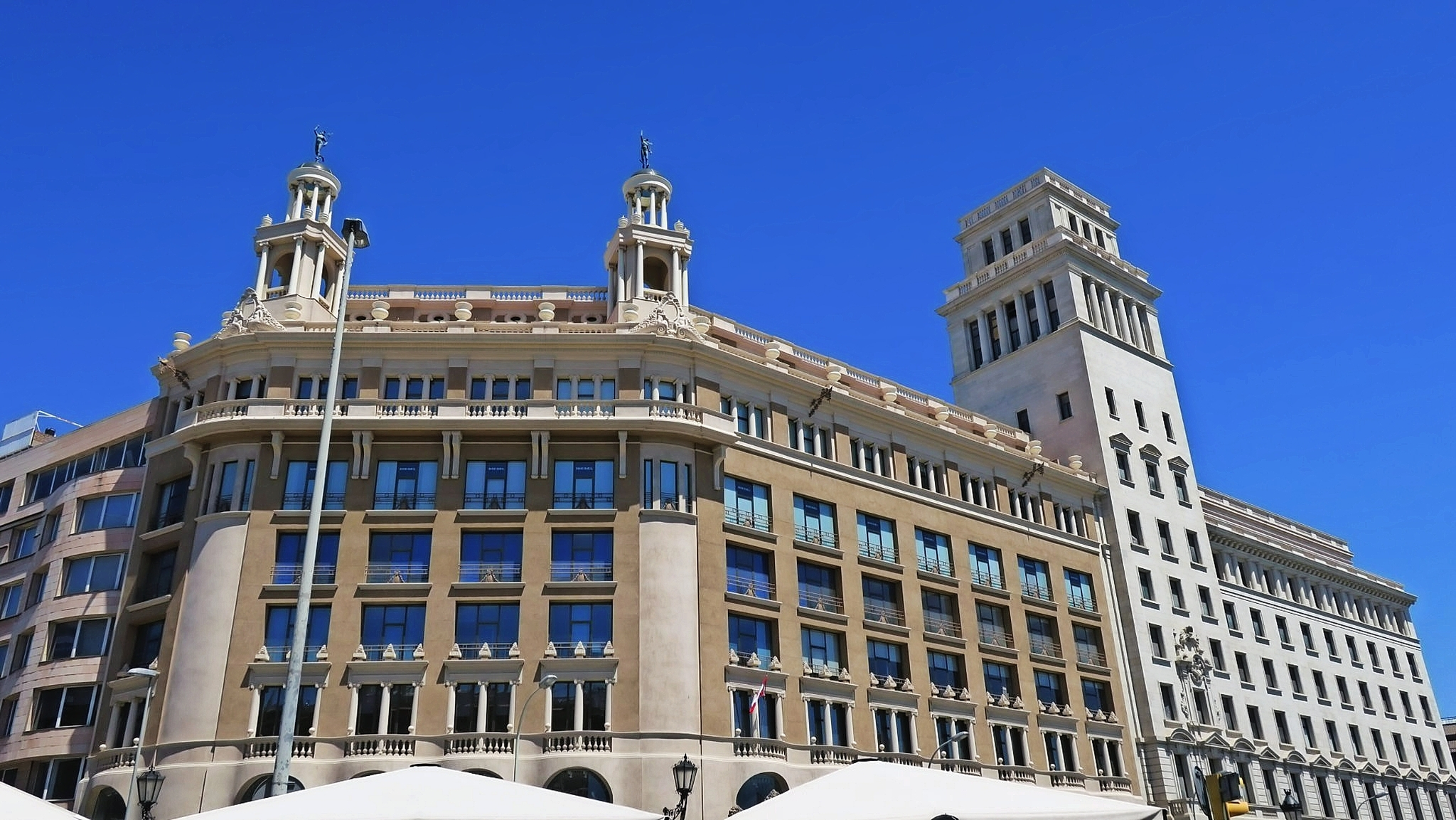 Barcelona in Katalonien, Spanien Altes Gebäude mit klassischer Architektur und zwei Türmen auf dem Dach unter klarem blauem Himmel.