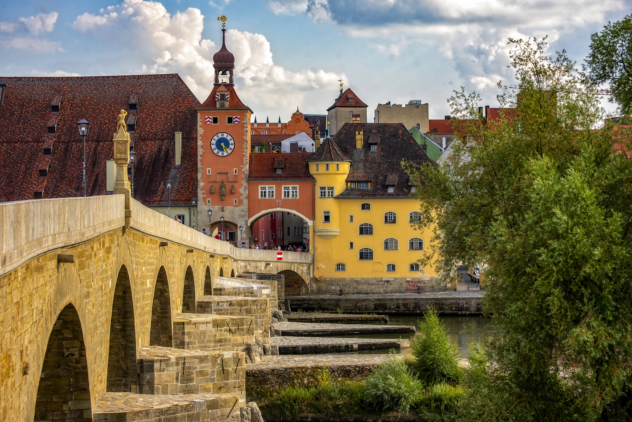 Altstadt von Regensburg mit der Steinernen Brücke Steinerne Brücke und historische Gebäude in Regensburg bei bewölktem Himmel.