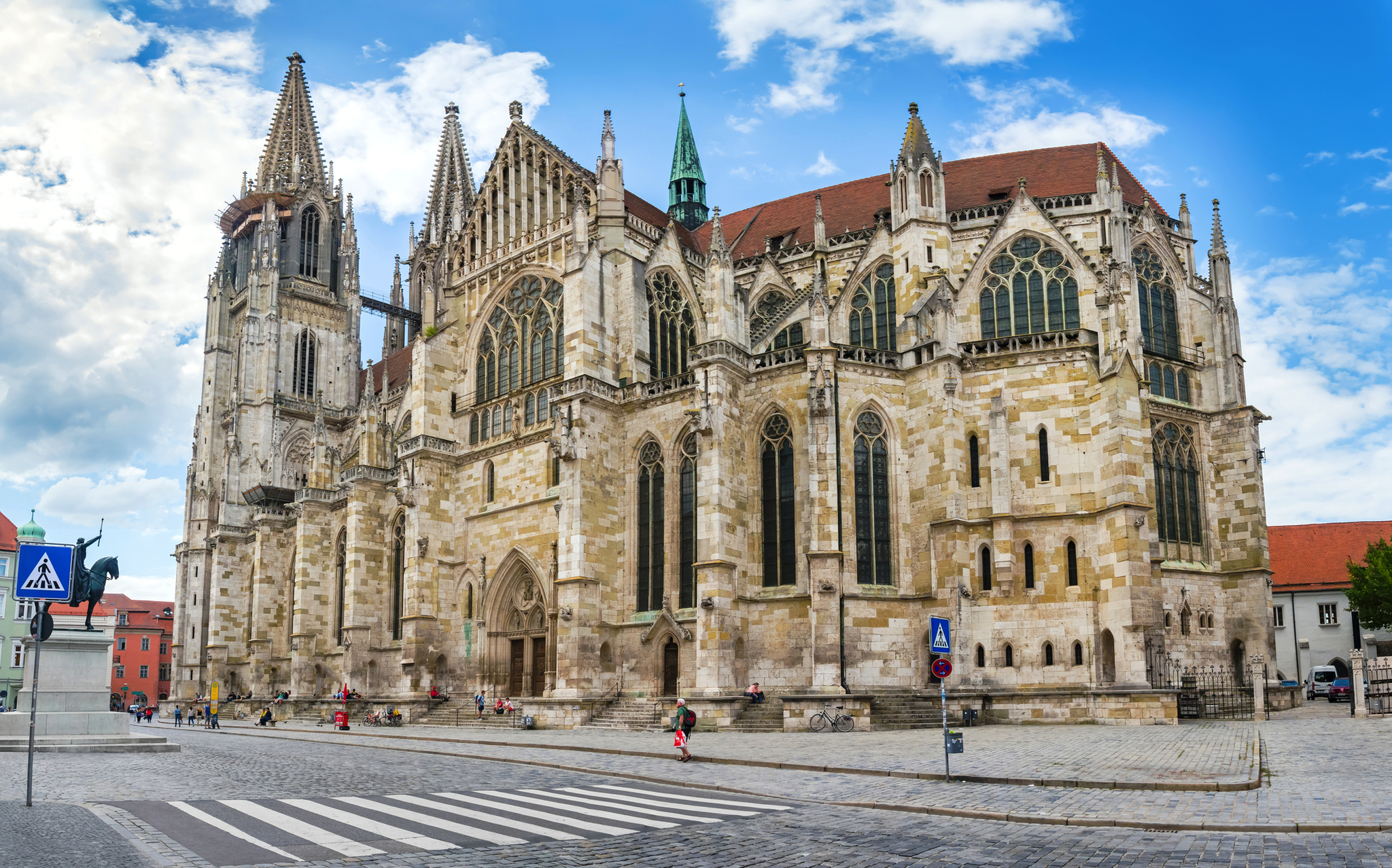 Dom St Peter in Regensburg Gotische Kathedrale bei blauem Himmel mit Personen auf einer Kopfsteinpflasterstraße.
