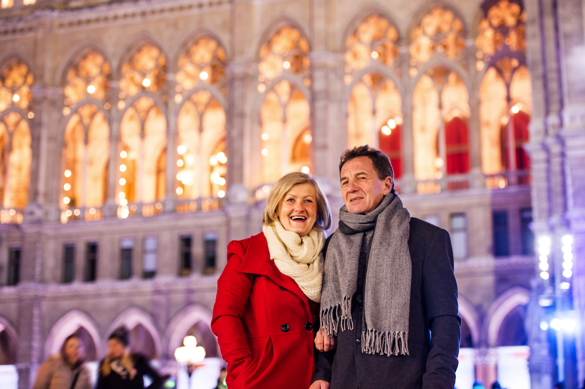 winterliches Rathaus in Wien, Österreich Ein lächelndes Paar vor einem beleuchteten historischen Gebäude.