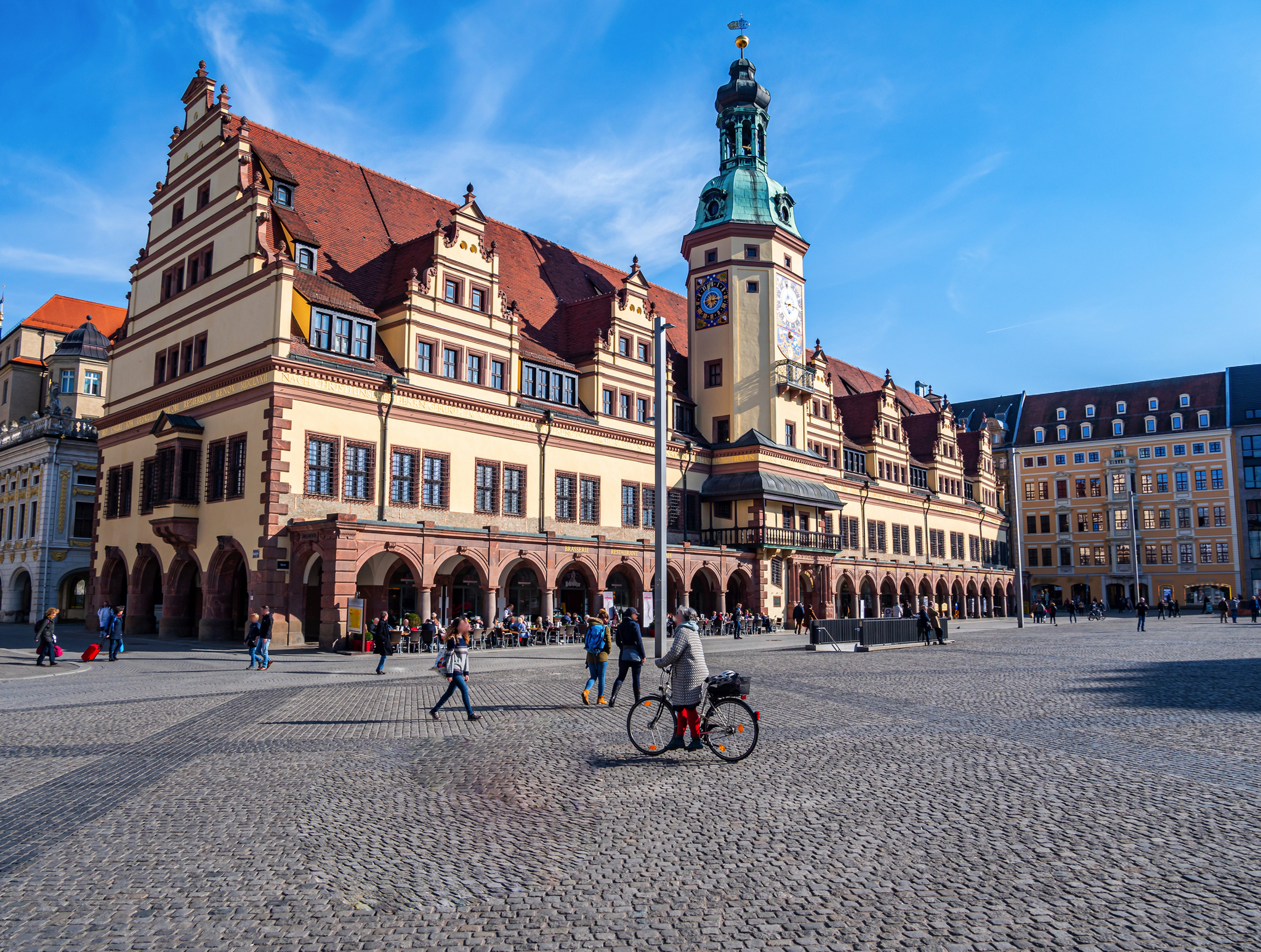 Leipziger Rathaus mit Marktplatz im Zentrum Historisches Gebäude mit Turm auf großem, belebtem Platz bei blauem Himmel.