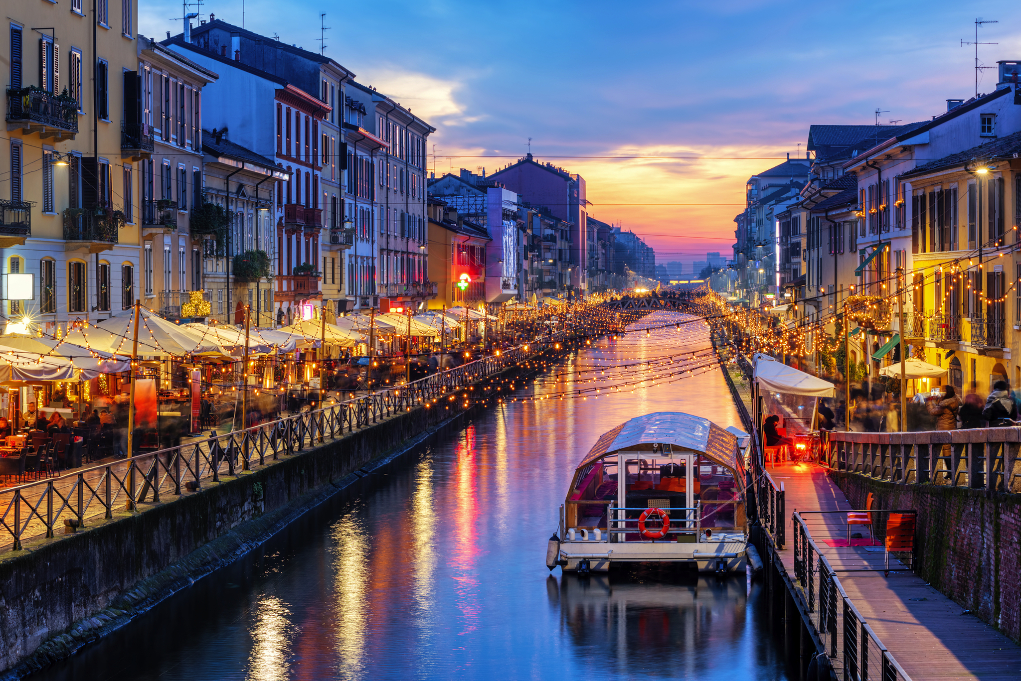 Navigli-Viertel in Mailand bei Sonnenuntergang Kanal mit Booten und beleuchteten Cafés in einer Stadt bei Abenddämmerung.