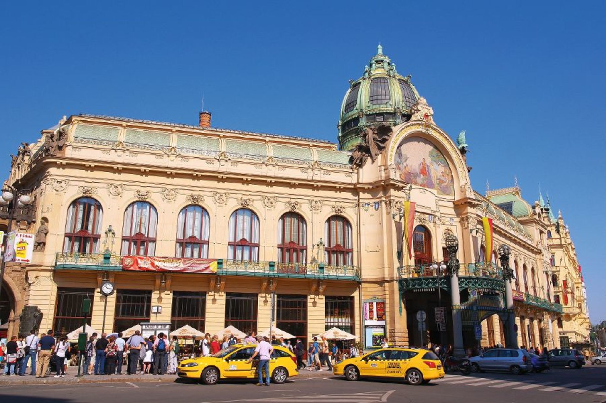 Historisches Gebäude mit Kuppel in Prag, Menschen und Taxis davor.