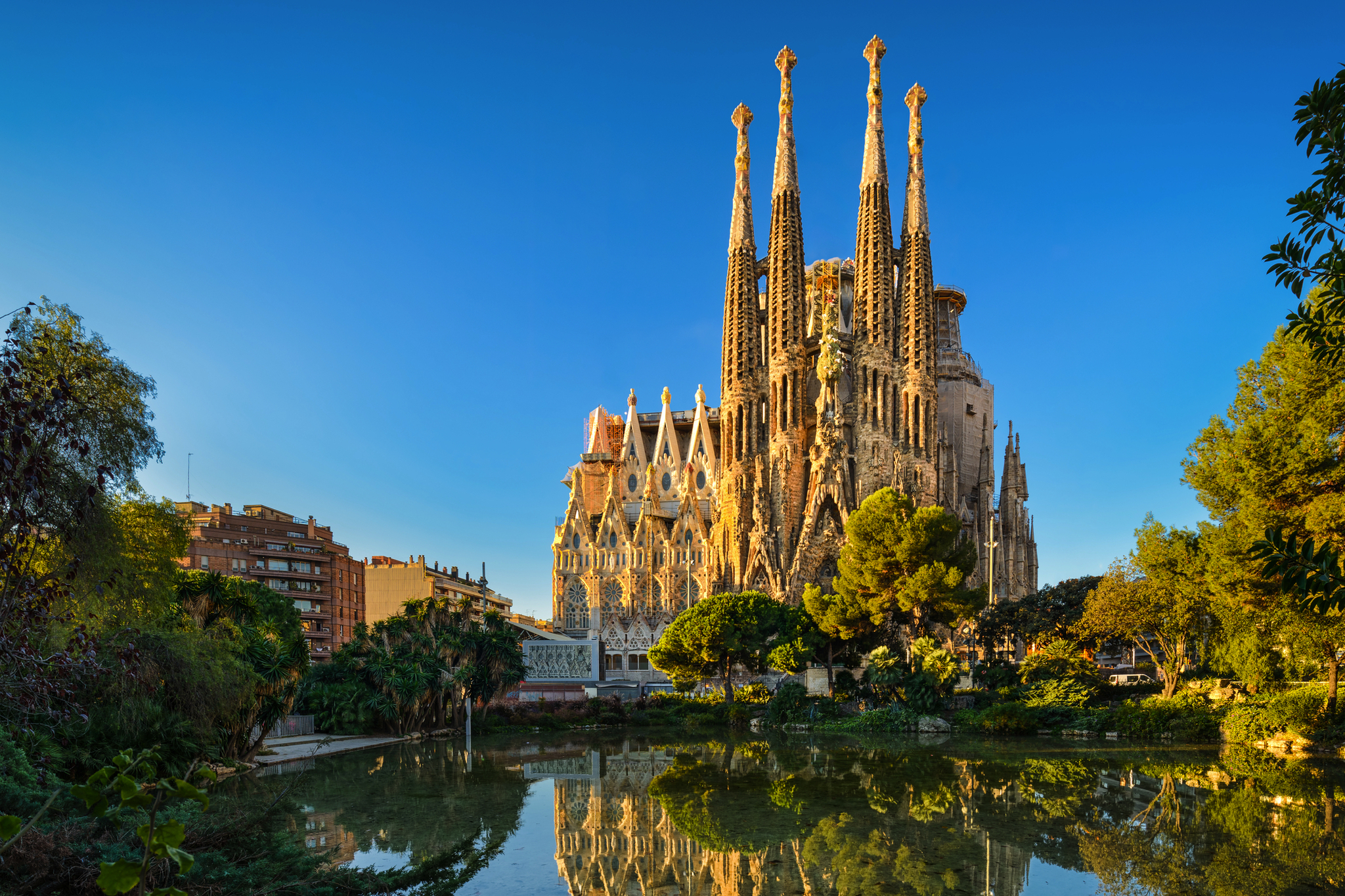 Sagrada Familia in Barcelona Kathedrale mit hohen Türmen und Spiegelung im Wasser bei klarem Himmel.