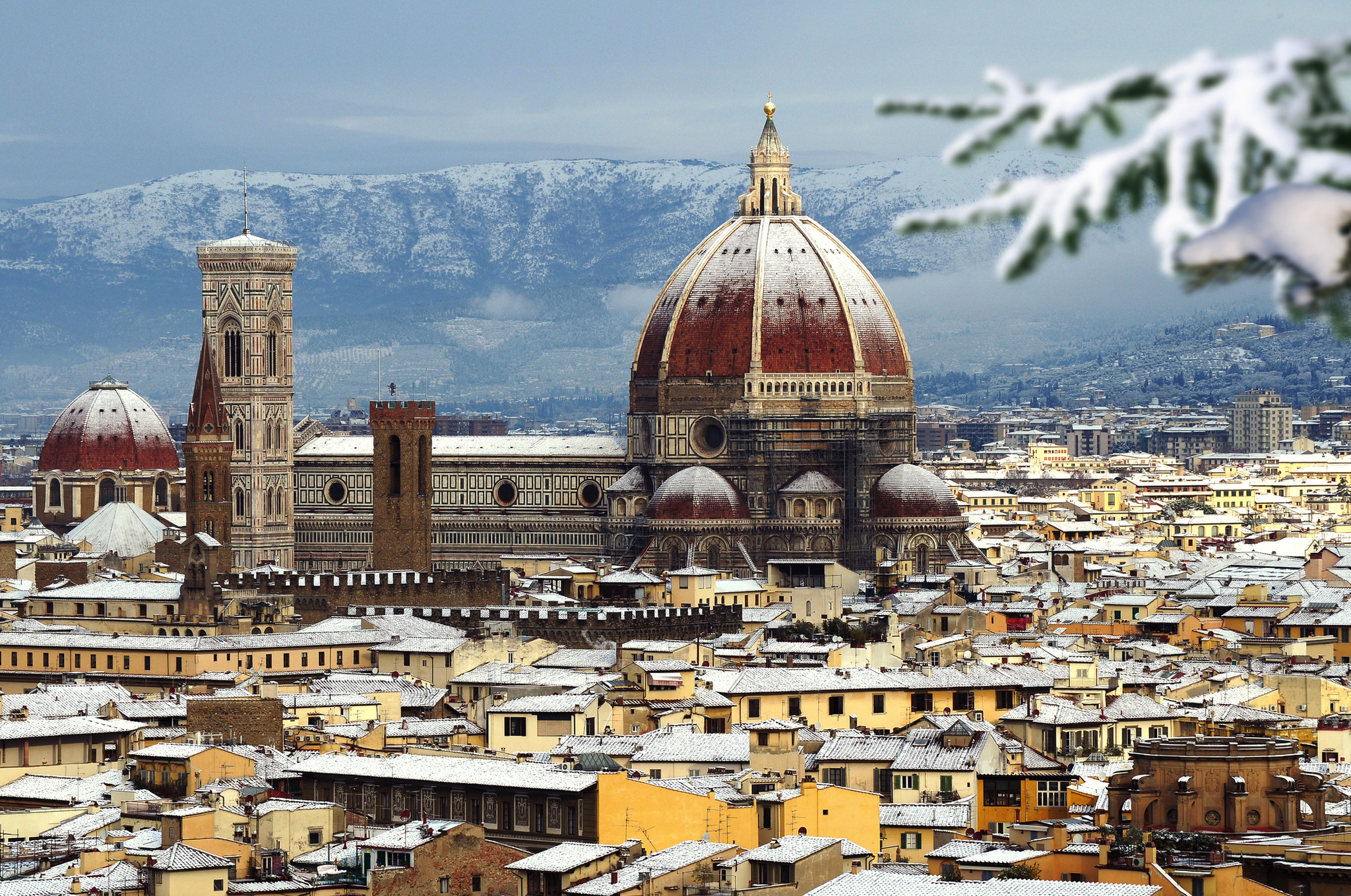 Florenz im Winter, schneebedeckte Dächer, Dom und Berge im Hintergrund.