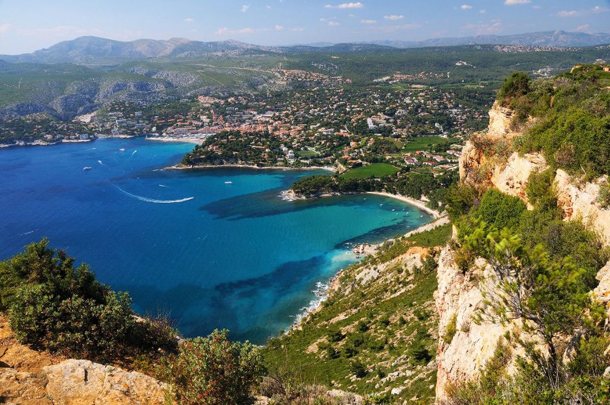 Küstenlandschaft mit Meer und Klippen, Stadt im Hintergrund, blauer Himmel.