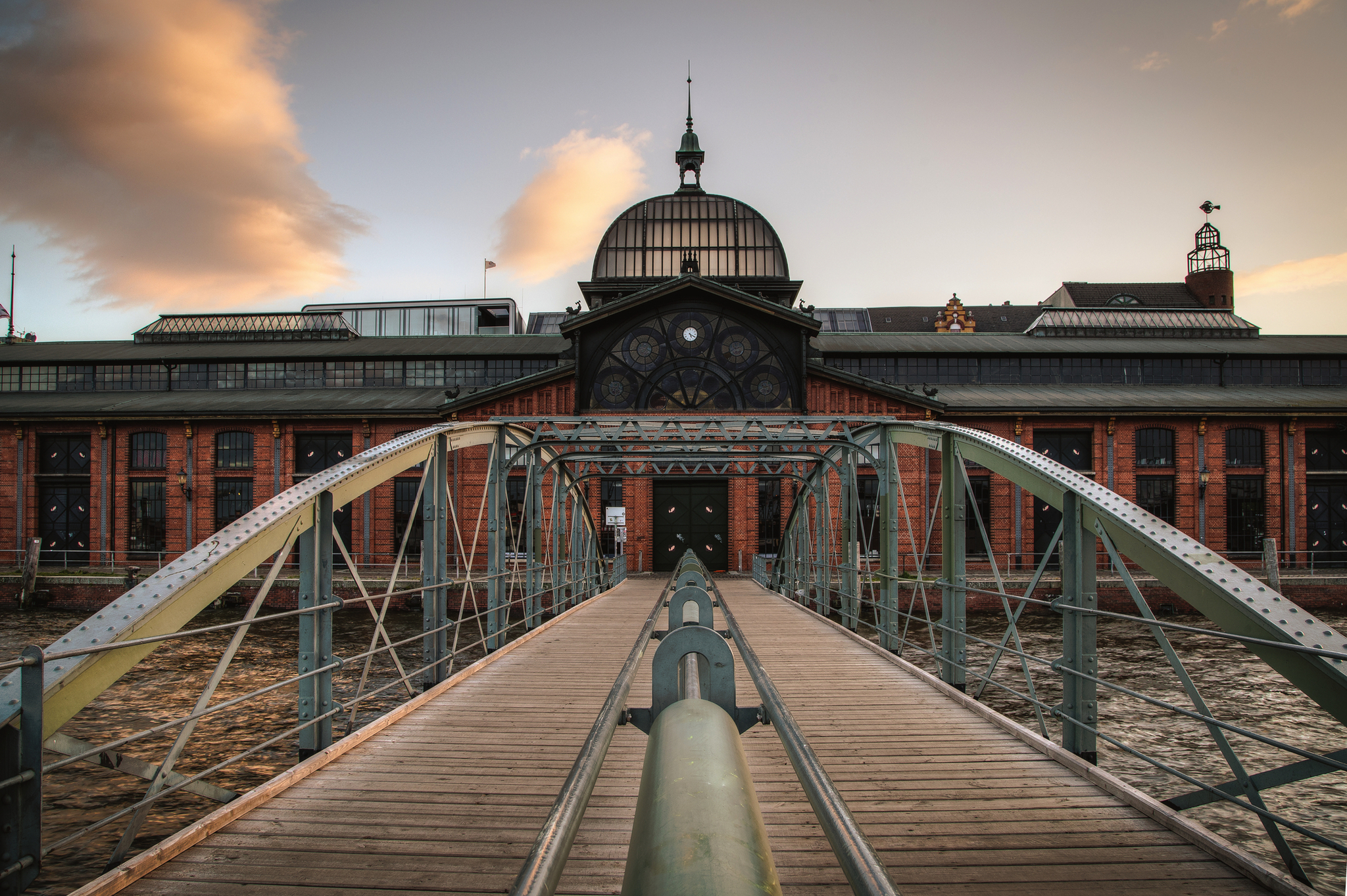 Fischmarkthalle in Hamburg Fischauktionshalle in Hamburg mit Brücke im Vordergrund bei Sonnenuntergang.