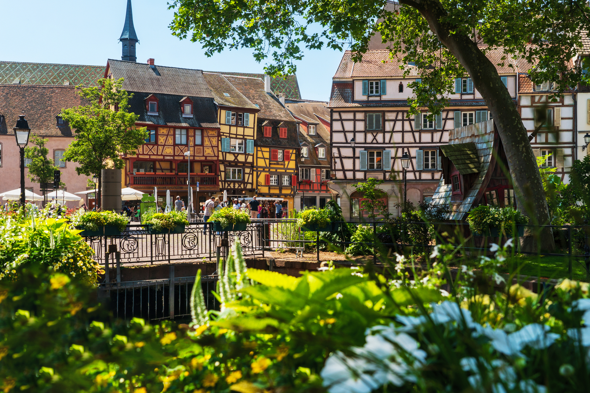 Fachwerkhäuser an einem sonnigen Tag im historischen Stadtzentrum mit Brücke und Blumen.