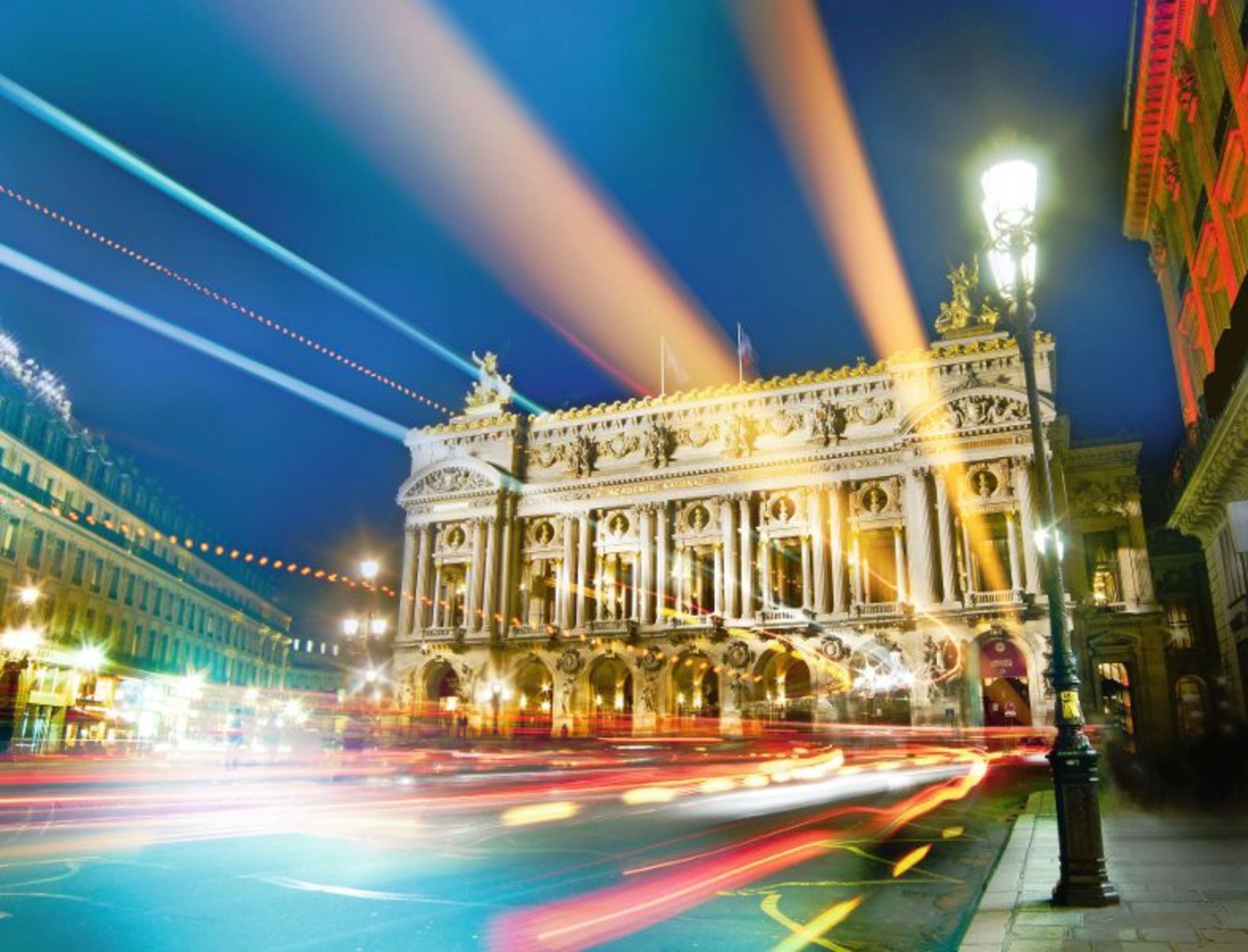 Historisches Gebäude bei Nacht mit Lichtspuren vorbeifahrender Autos.