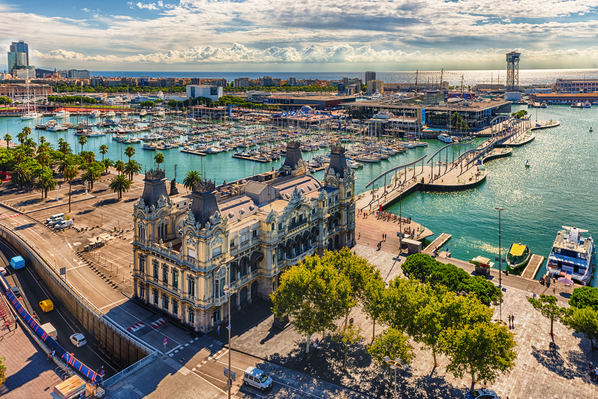 Hafen von Barcelona mit historischem Gebäude und Yachten im Wasser.