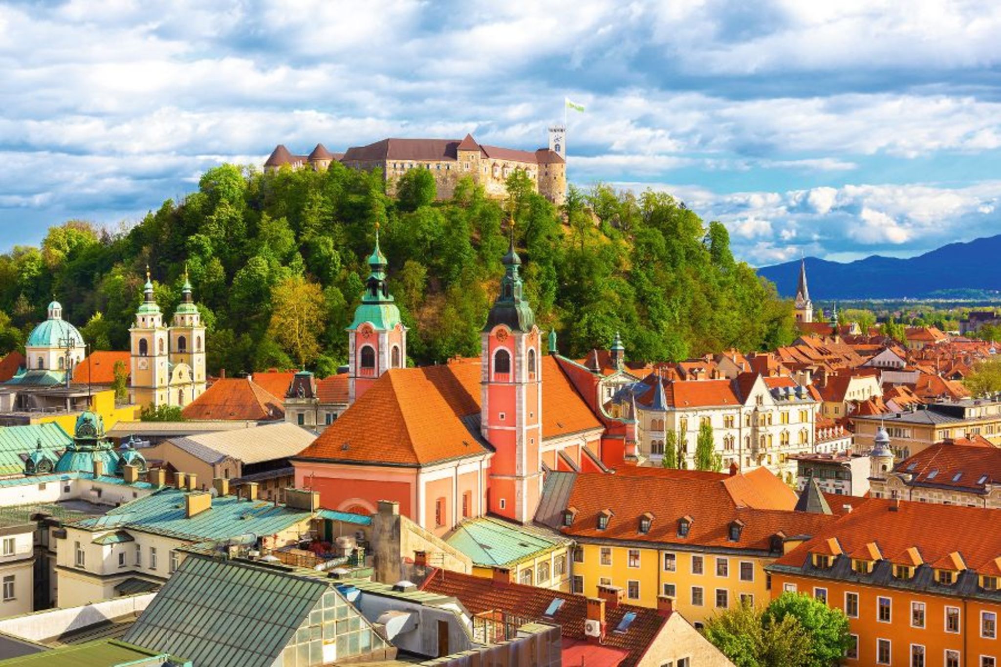 Panorama von Ljubljana Blick auf Ljubljana mit Burg auf Hügel und bunten Häusern im Vordergrund.