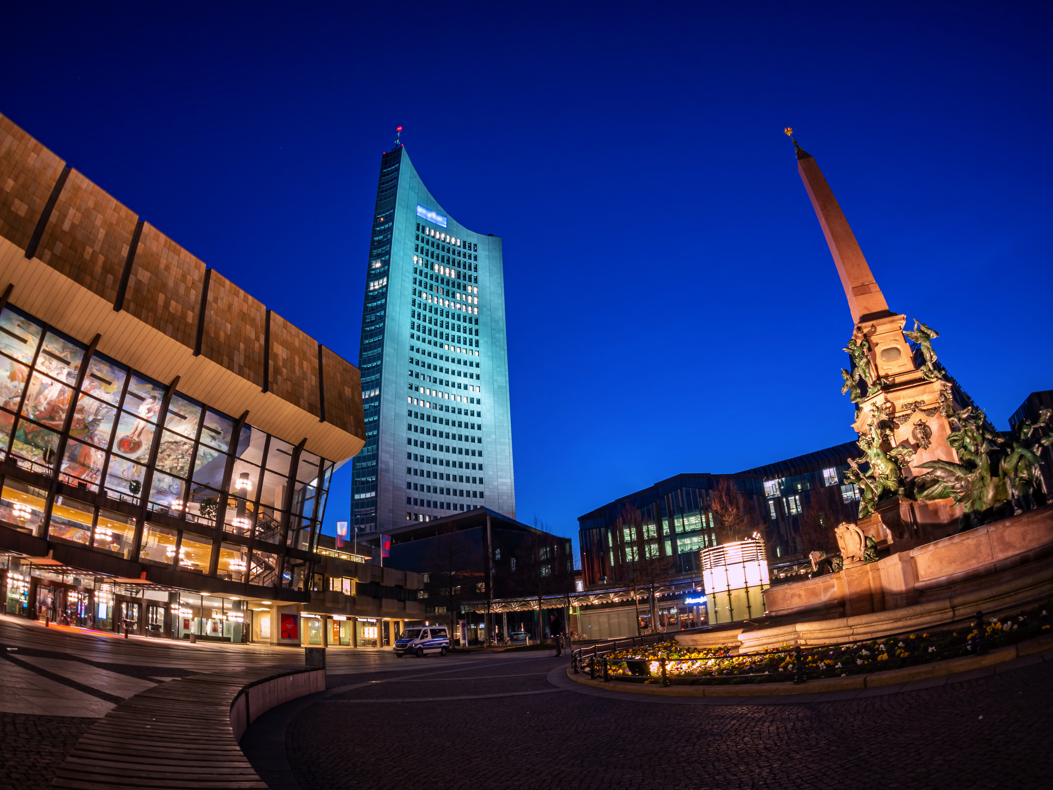 Platz mit Gebäuden und einem hohen Turm bei Nacht.