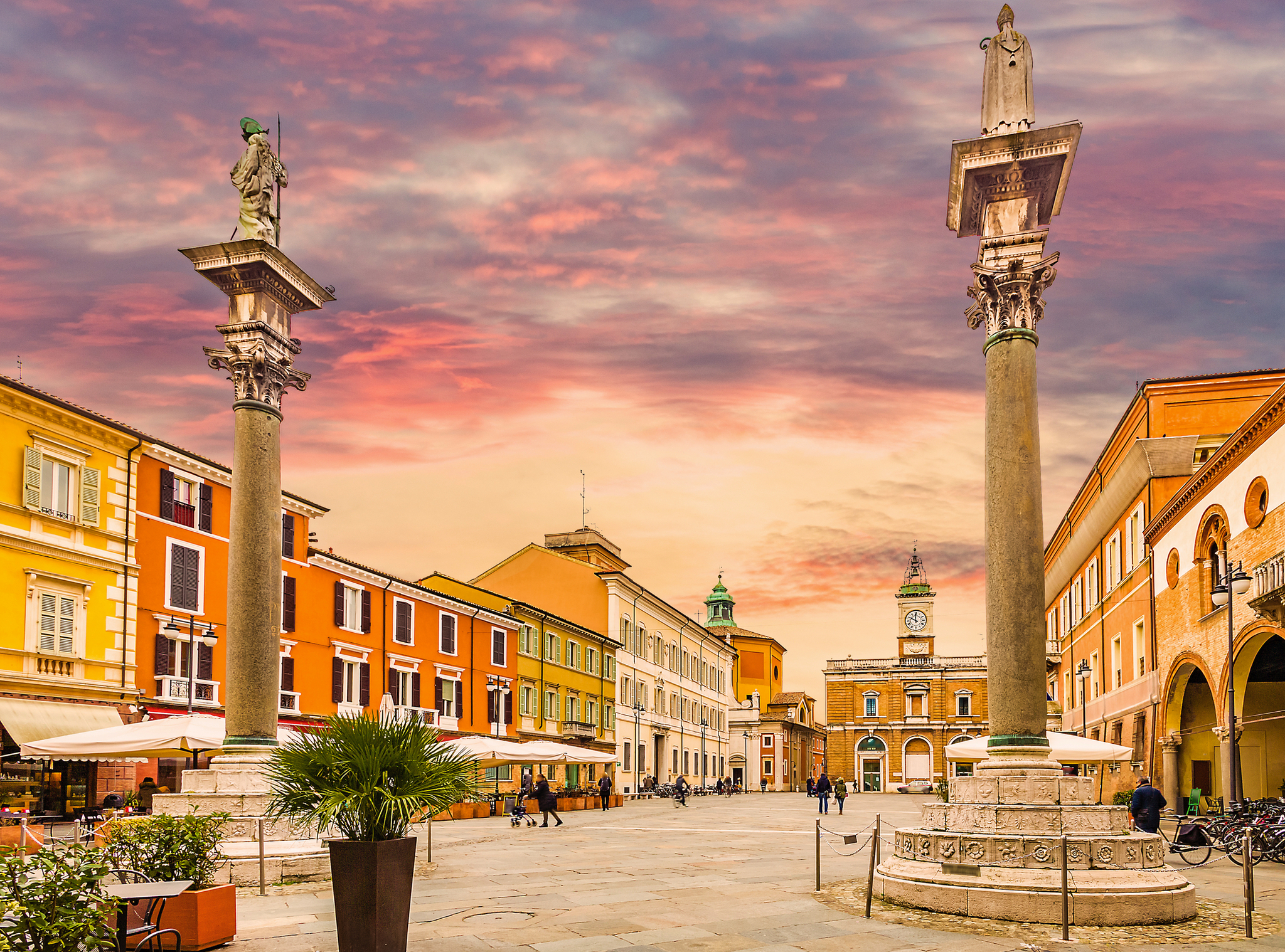 Historischer Platz mit Säulen und farbigen Gebäuden bei Sonnenuntergang.