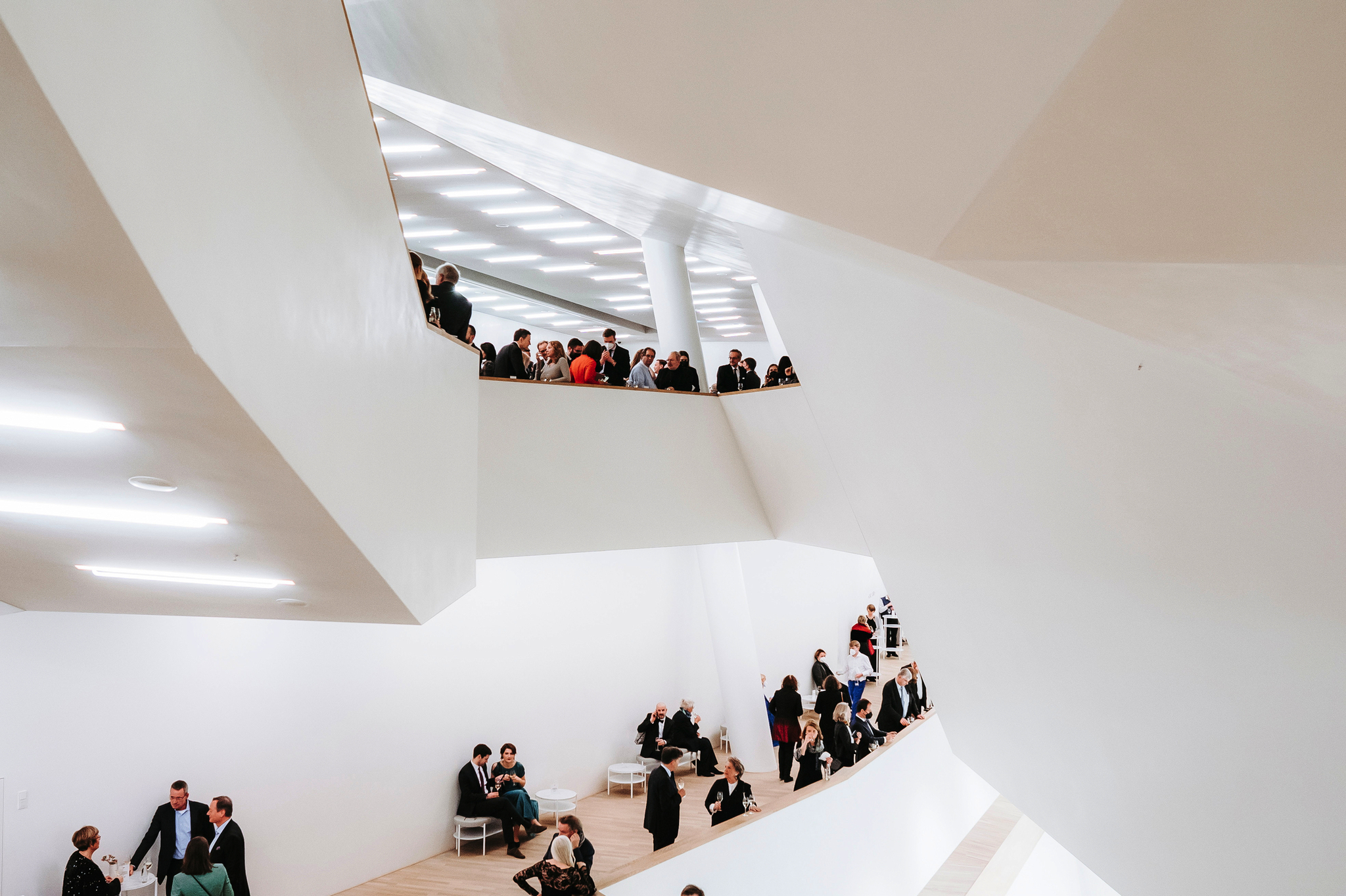Menschen in einem modernen, weißen Treppenhaus bei einer Veranstaltung.