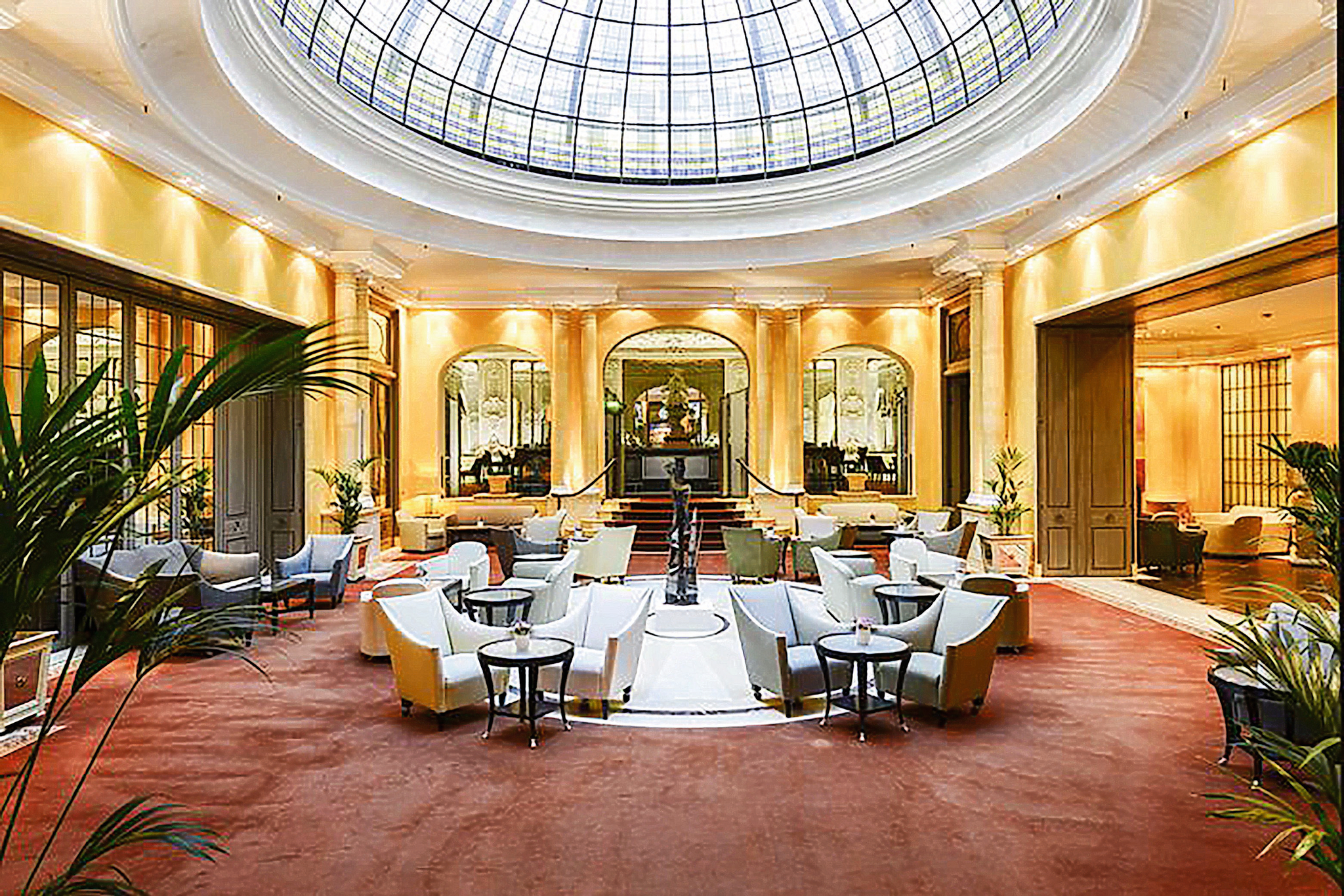 Eleganter Atriumbereich im Hotel Bayerischer Hof, München, mit Sitzgruppen und Glaskuppel.