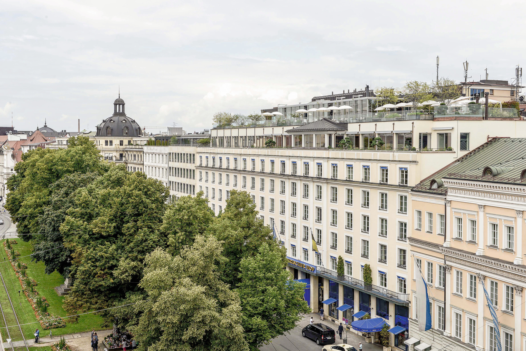Vorderansicht des Hotels Bayerischer Hof in München mit Bäumen und Strasse.