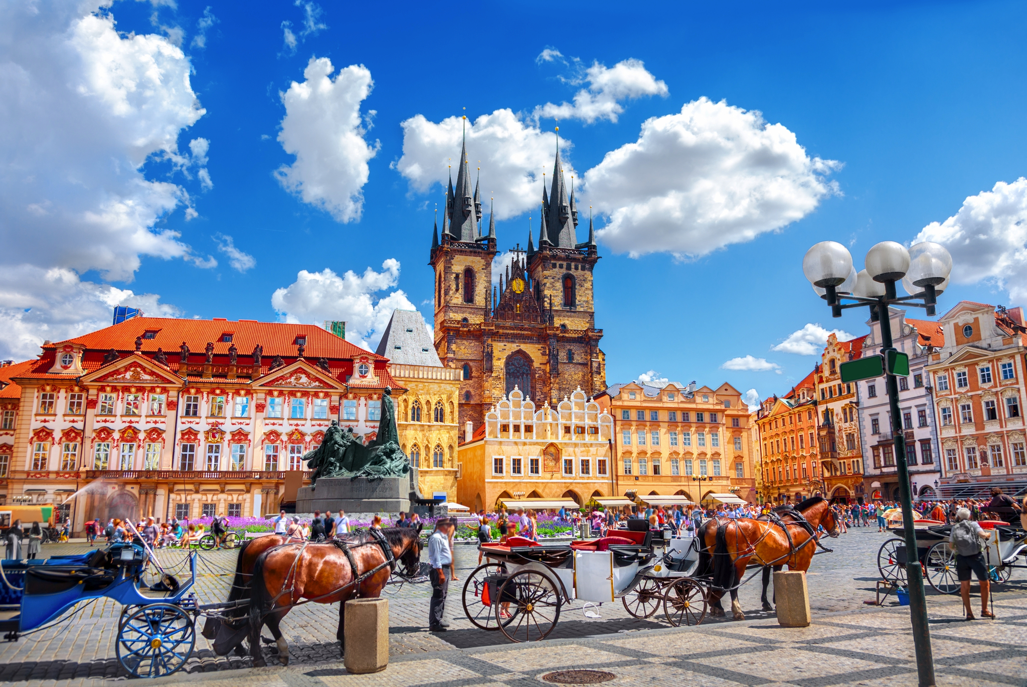 Historischer Platz mit Pferdekutschen und gotischer Kirche.
