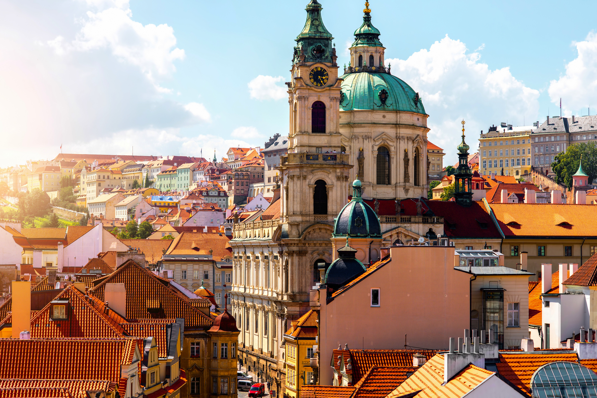 Ansicht von Prag mit Sankt-Nikolaus-Kirche und bunten Gebäuden bei sonnigem Wetter.