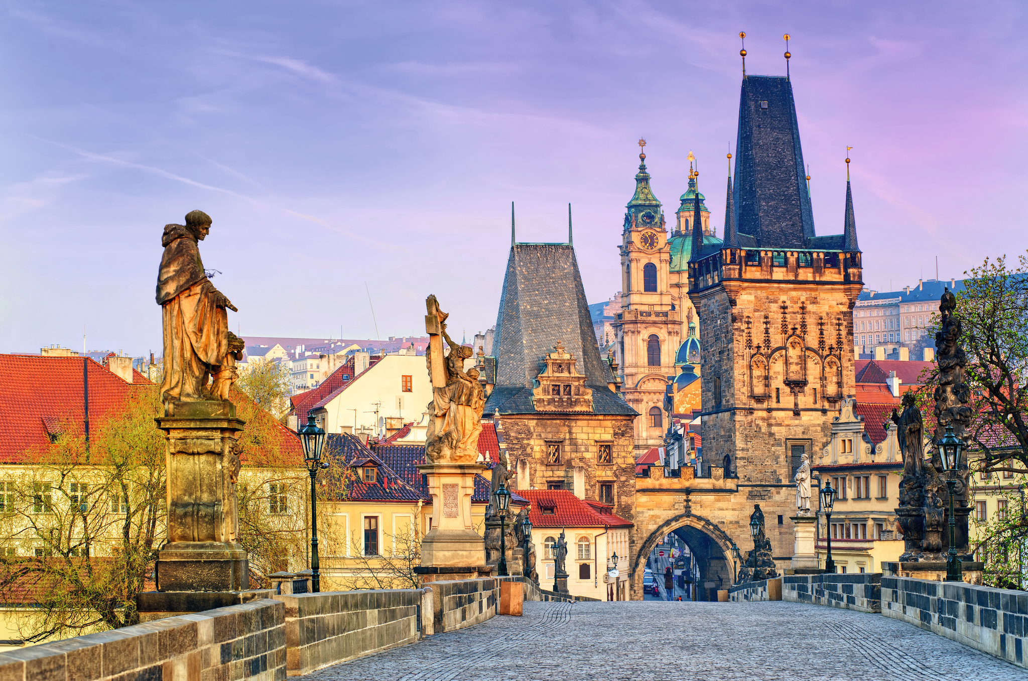 Historische Brücke mit Statuen und alten Gebäuden im Hintergrund.