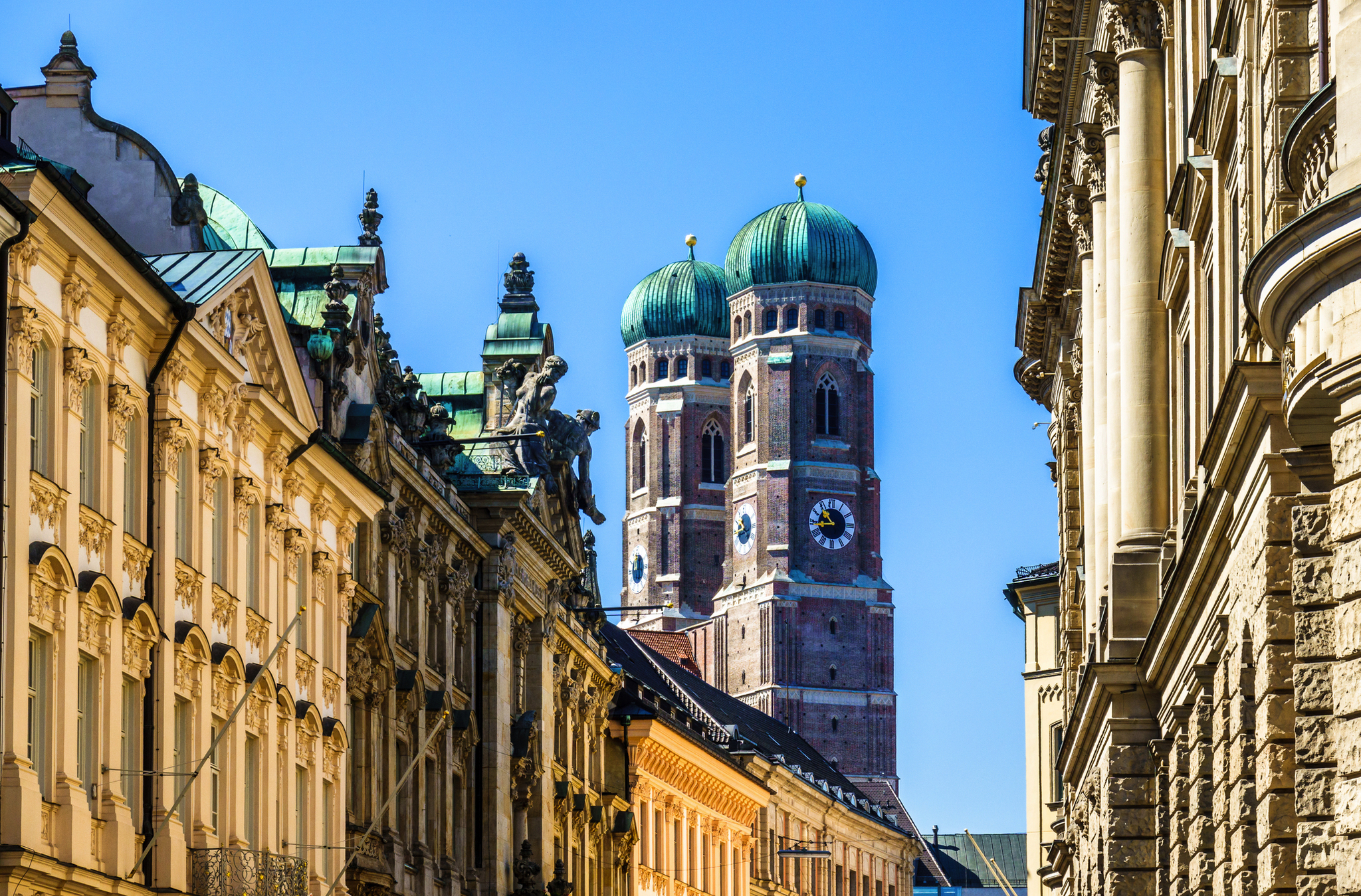 Straßenansicht mit der Frauenkirche in München im Hintergrund.