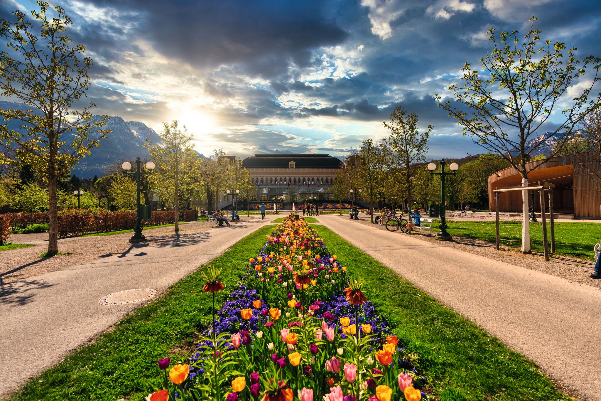 Garten mit blühenden Blumen im Vordergrund und monumentalem Gebäude im Hintergrund.