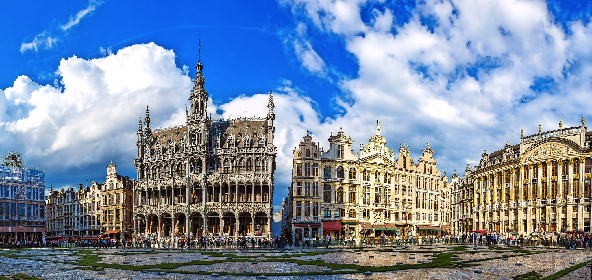 Historische Gebäude und blauer Himmel auf einem belebten Platz.
