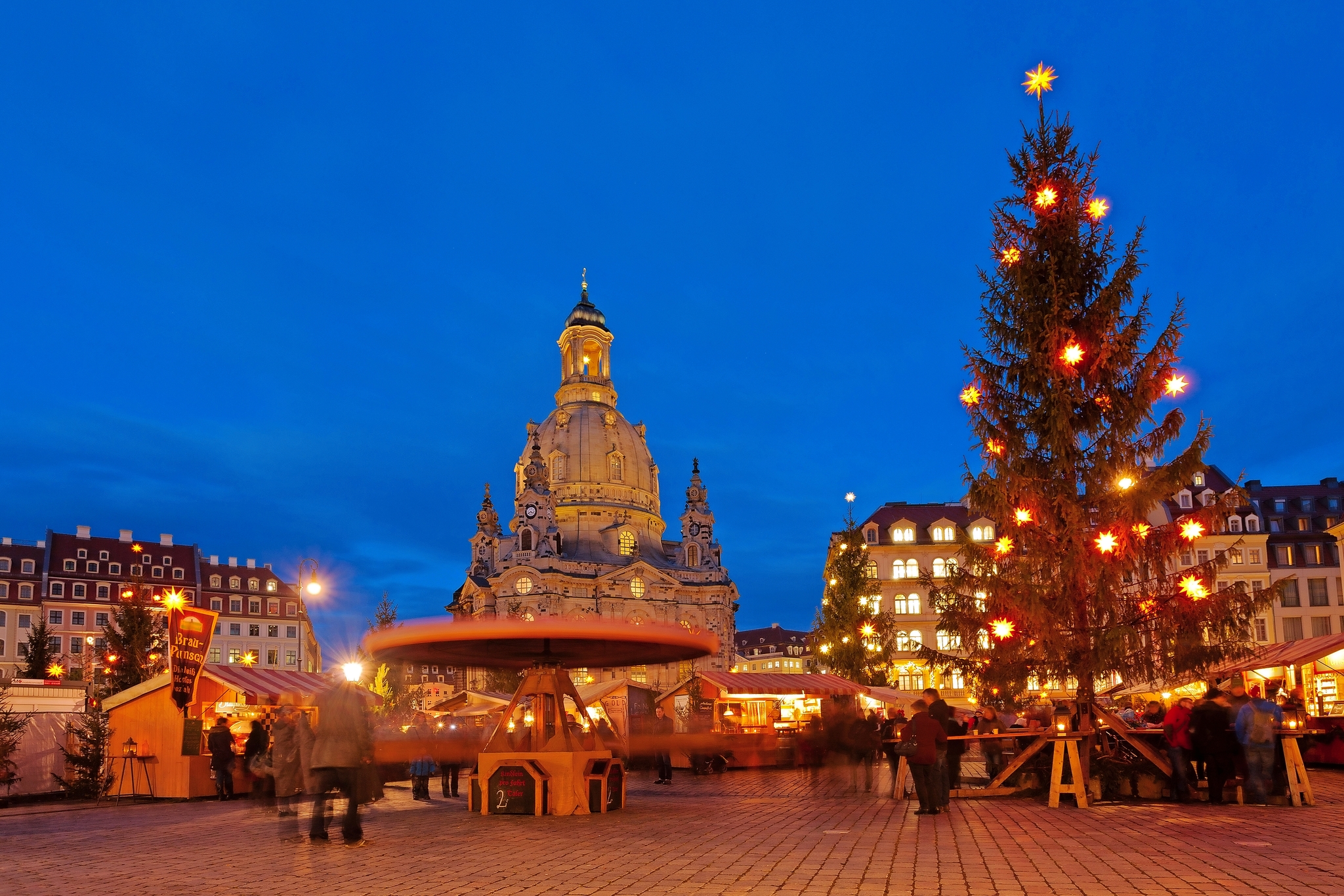 Weihnachtsmarkt am Abend vor historischer Kirche mit beleuchtetem Weihnachtsbaum