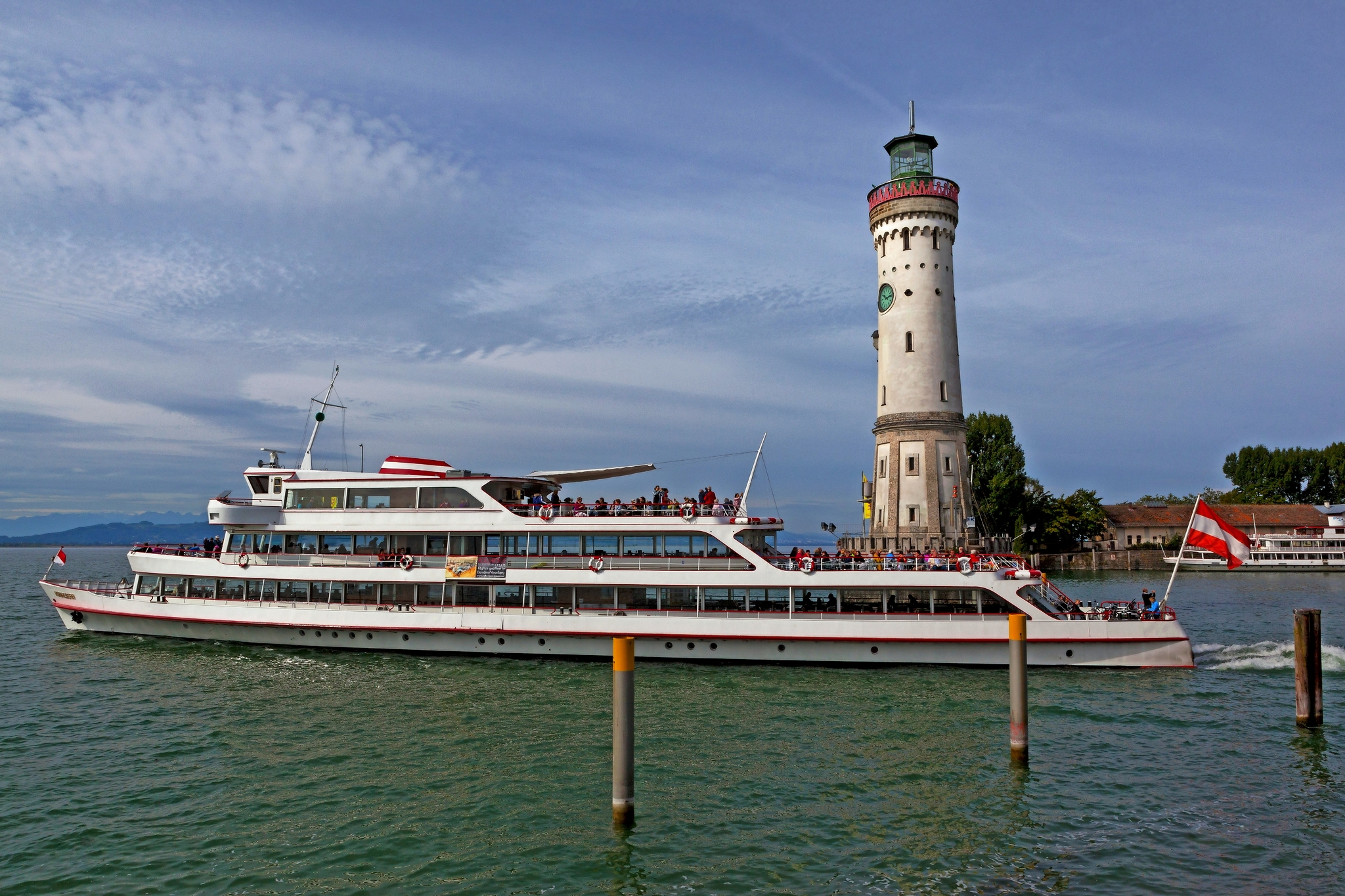 Ausflugsdampfer Vorarlberg, Leuchtturm, Lindau, Bodensee Ein Ausflugsschiff fährt an einem Leuchtturm auf einem See vorbei.
