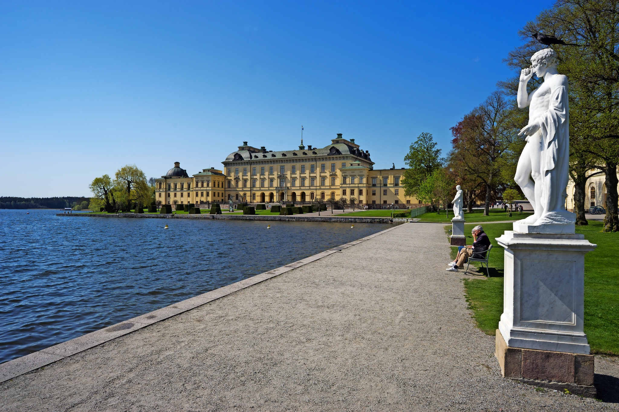 Schloss mit See und Statuen bei Sonnenschein