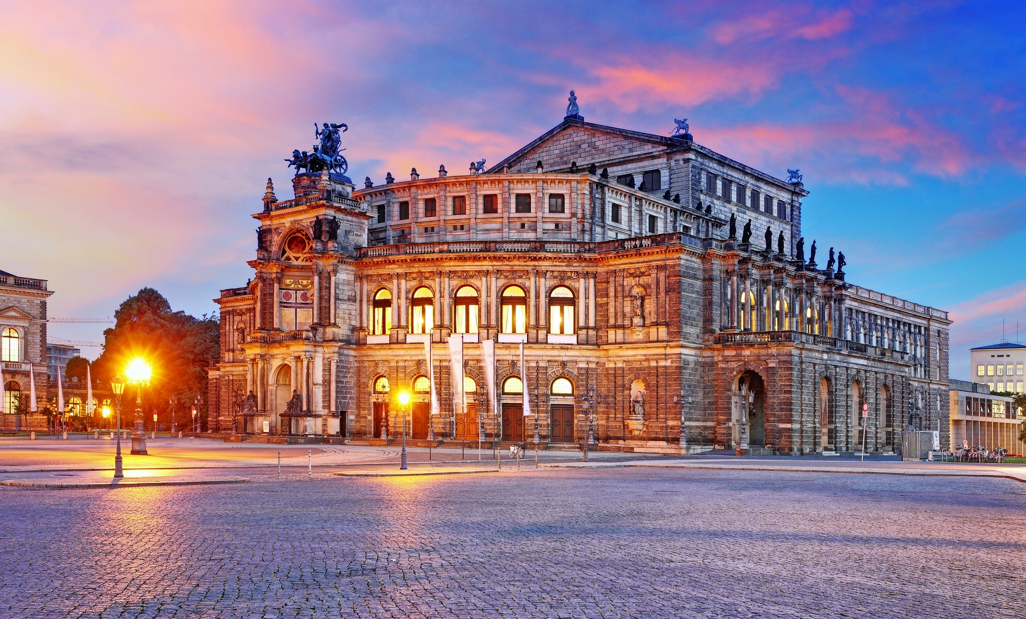 Historisches Gebäude bei Sonnenuntergang mit beleuchteten Fenstern.