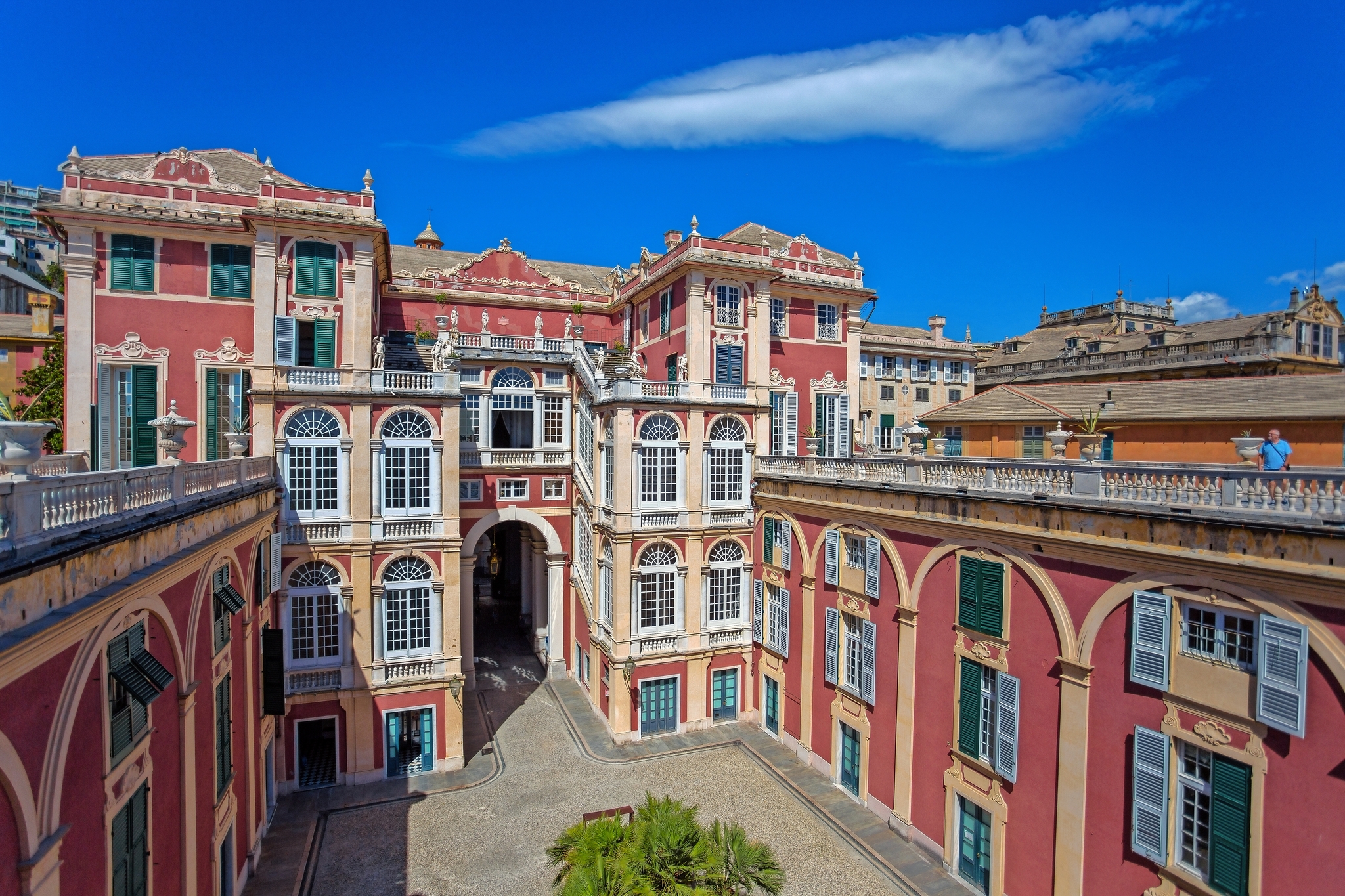 Palazzo Reale in Genua, Italien Historisches Gebäude mit rosa Fassade und blauen Fensterläden unter blauem Himmel.