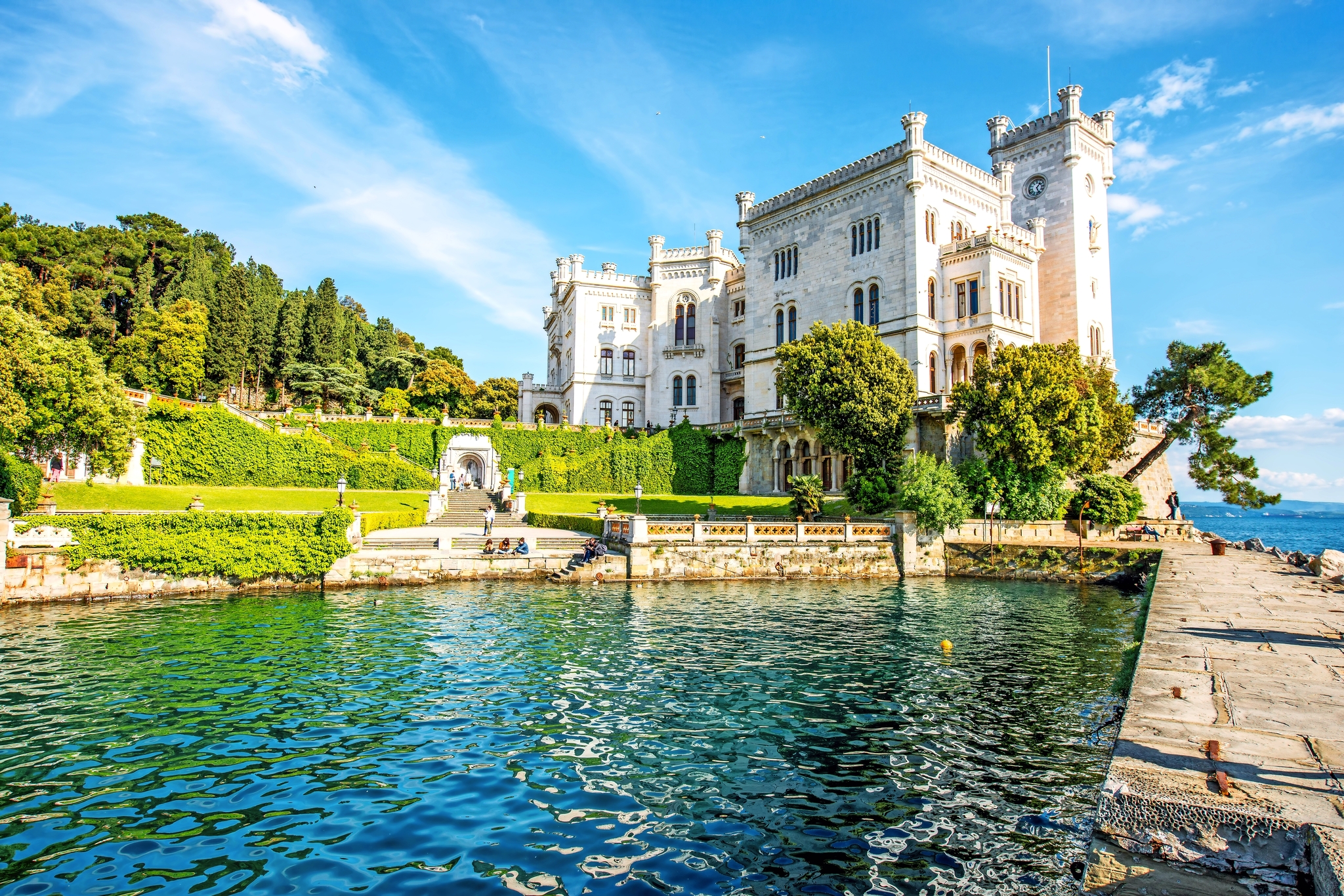 Schloss am Meer mit Garten und Promenade bei sonnigem Wetter