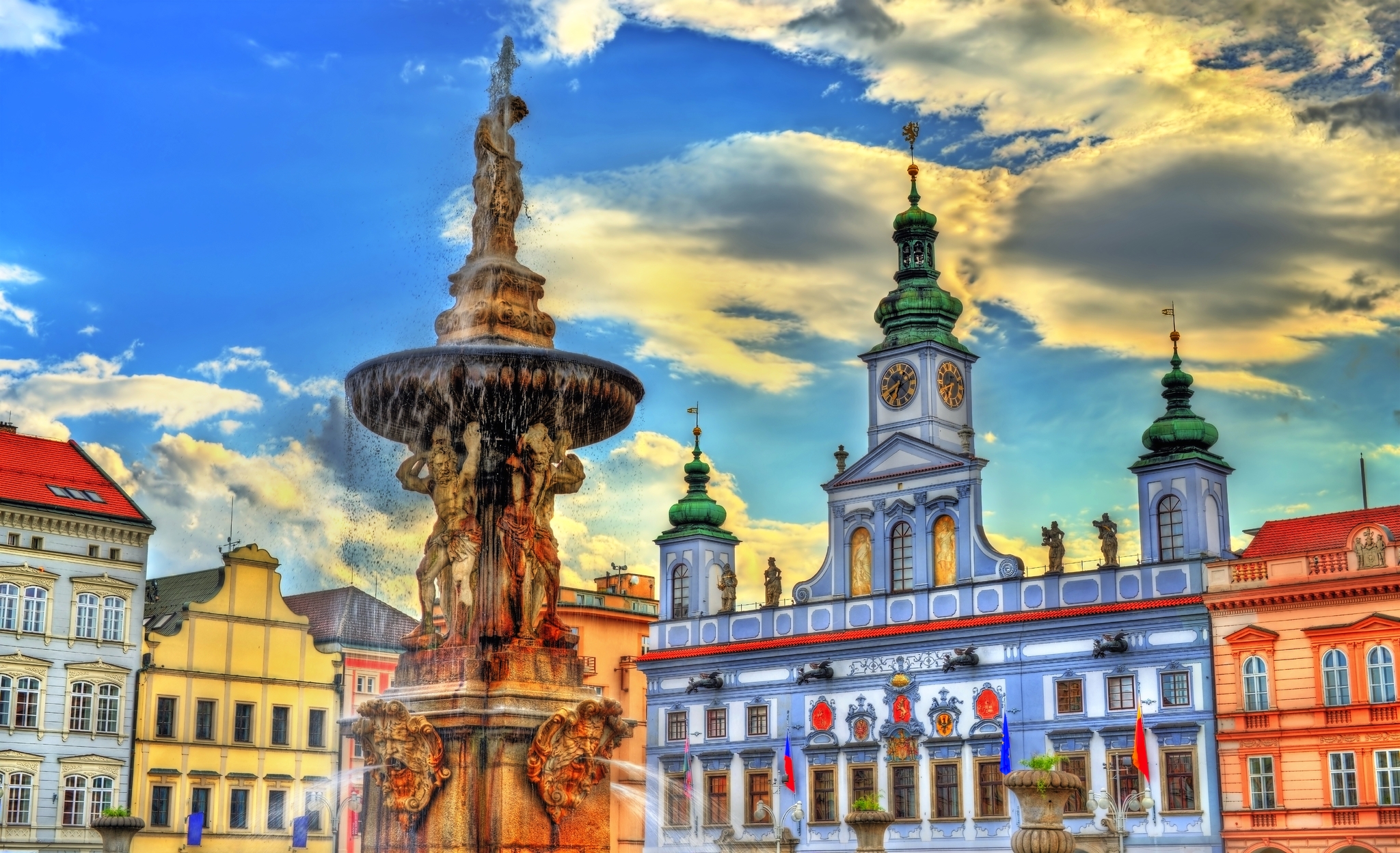 Historischer Brunnen und buntes Rathaus vor bewölktem Himmel