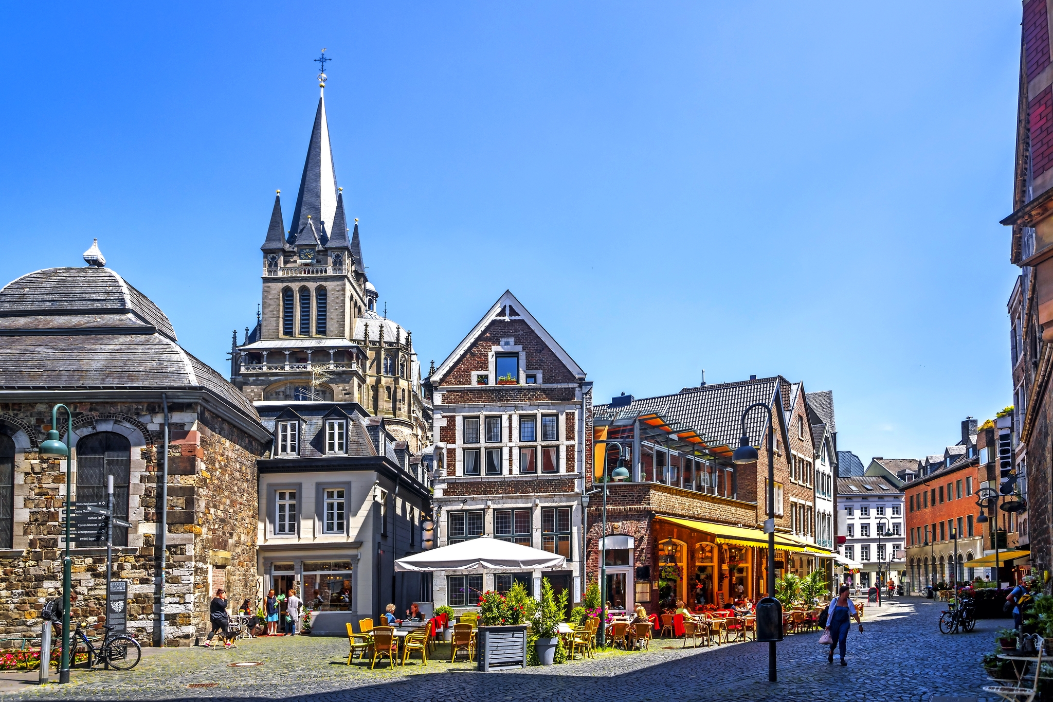 Historische Gebäude und Straßencafé bei sonnigem Wetter.